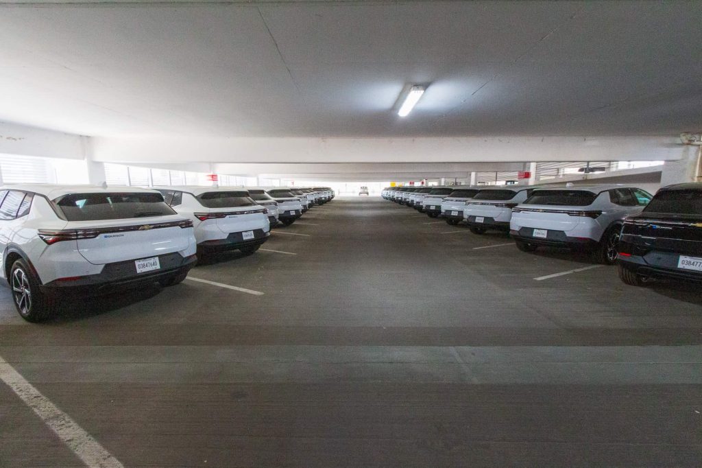 Parking ramp with all but one spot filled with white Chevrolet Equinoxes.