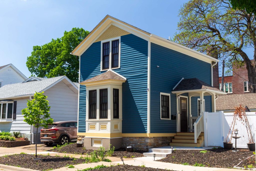 Two-level blue home, with unique architectural details including a bay window.