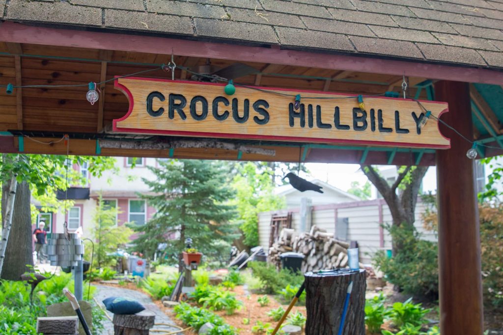 A wooden sign that reads "Crocus Hillbilly" attached to the pagoda in a backyard.