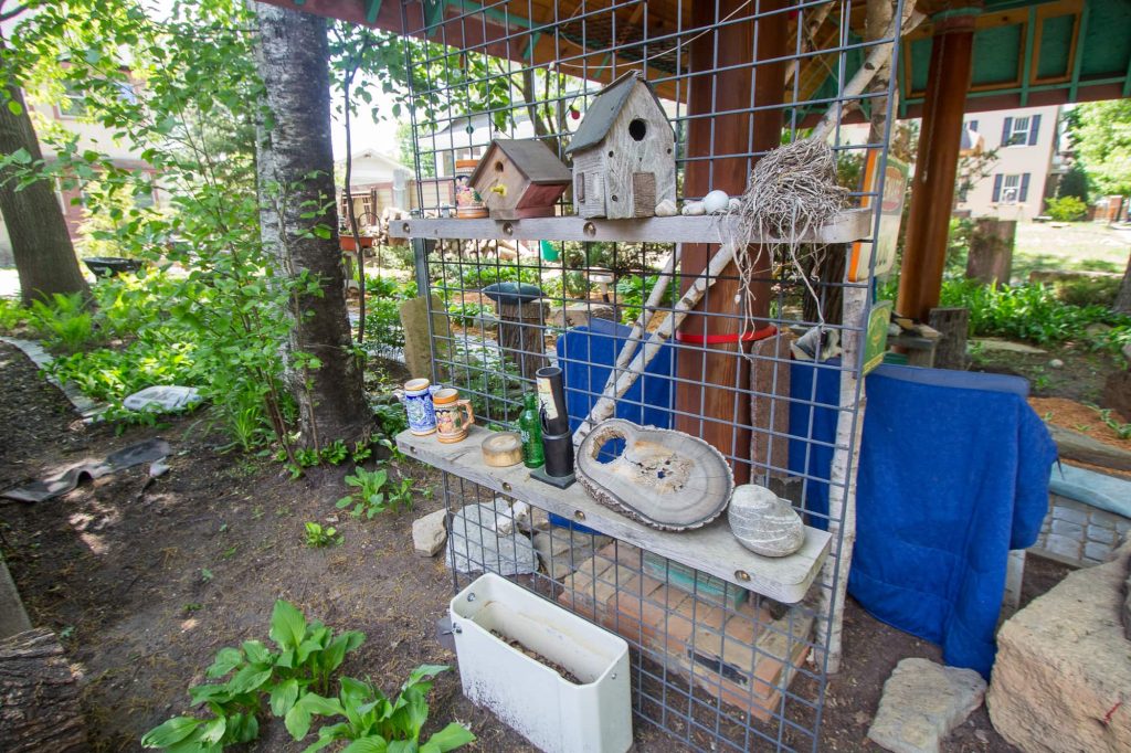 Two shelves display assorted items including two bird houses, a nest, three German beer steins and several rocks.