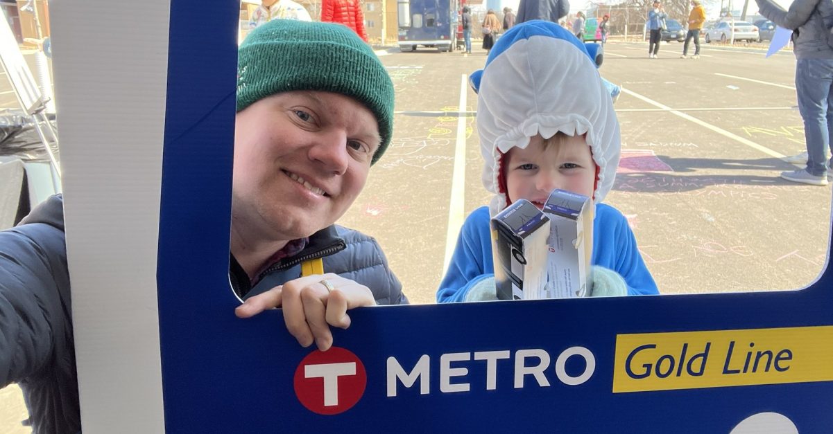 The author and his son posing behind a frame that reads "I rode the Metro Gold Line."