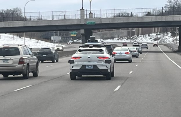 A dashboard view of I-94, with a Waymo vehicle in the next lane.