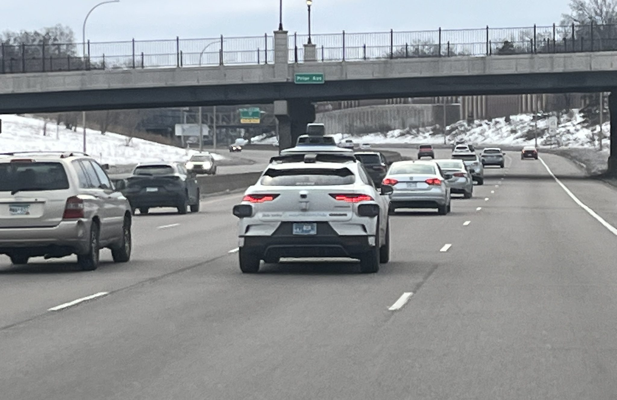 A dashboard view of I-94, with a Waymo vehicle in the next lane.