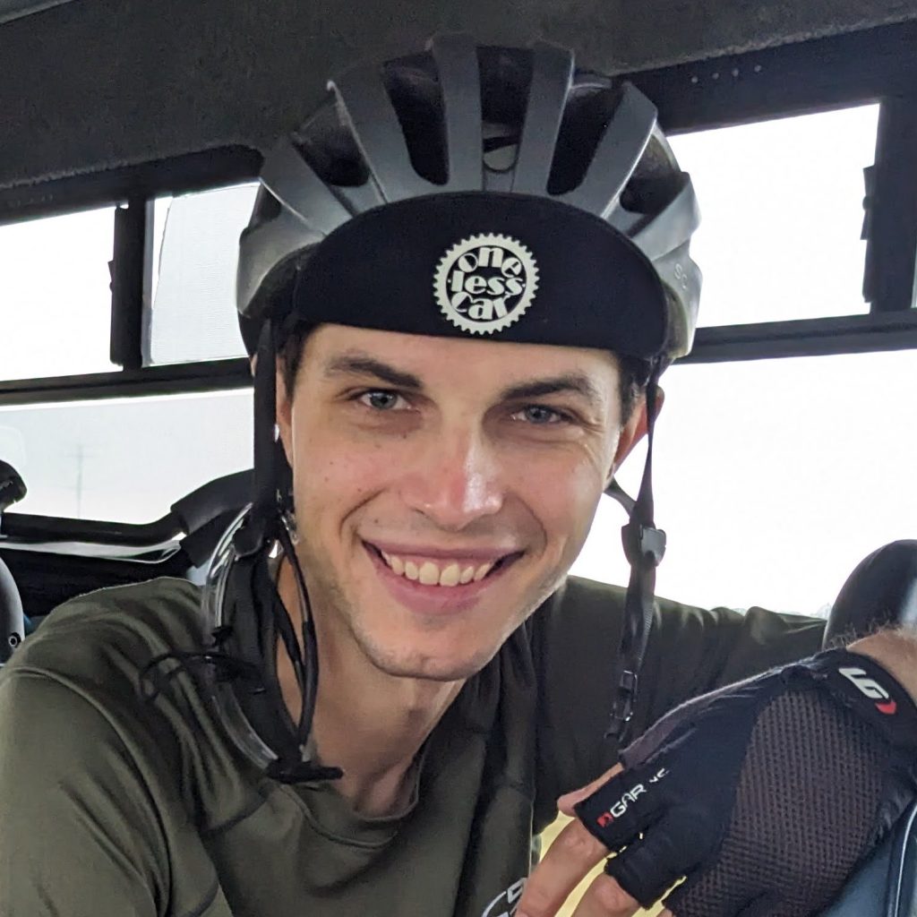 Ian Buck posing wearing a bike helmet while sitting in a bus