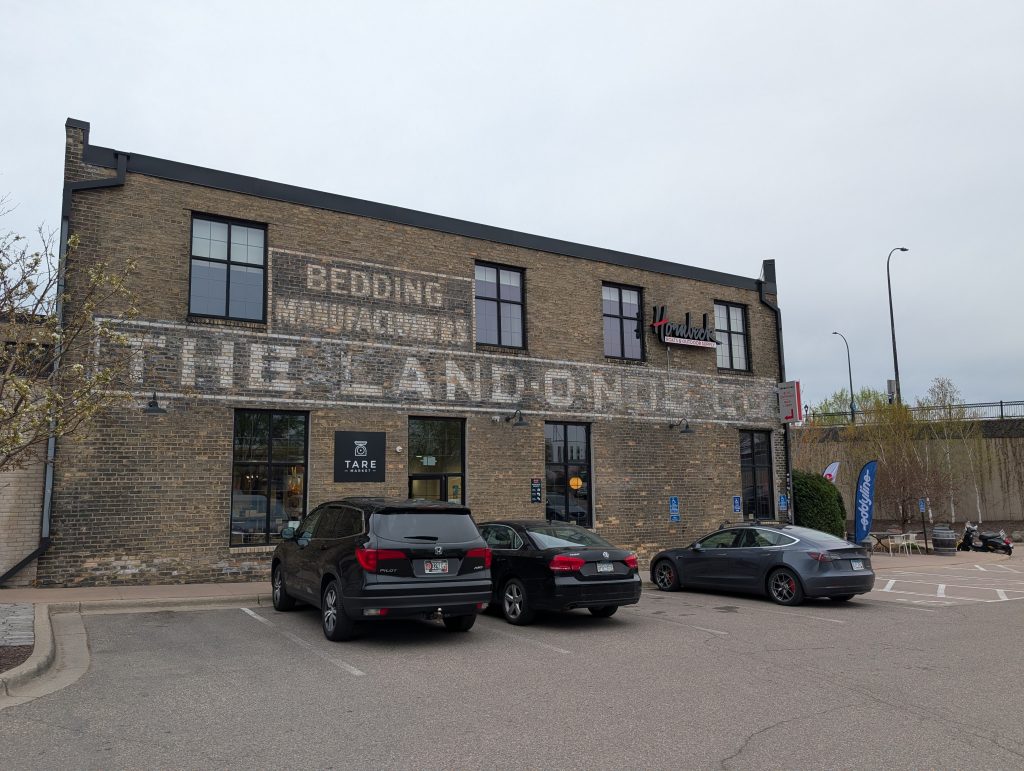 brick-faced two-story building with painted signage for The Land-o-Nod