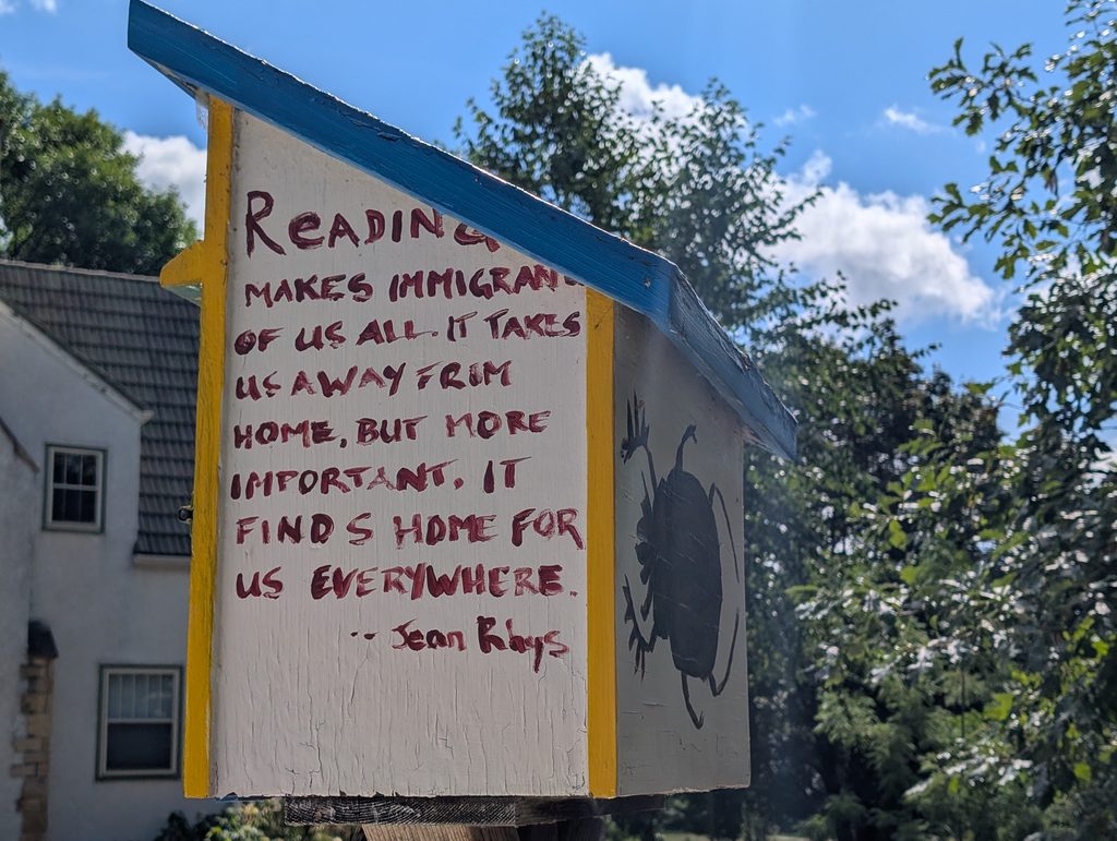 little free library viewed from a back corner with text on the side and a beetle on the back