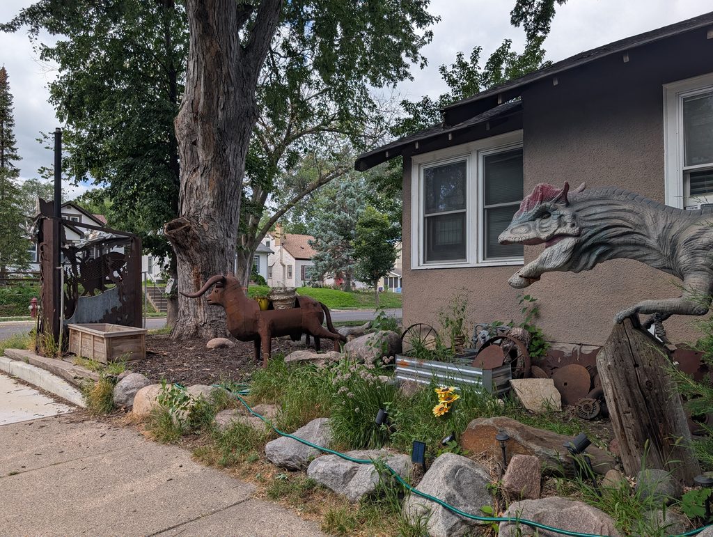 side yard with water buffalo, dinosaur, and other decor