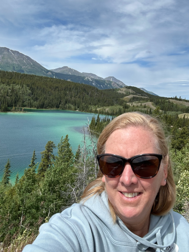 Selfie of Jan in a landscape of mountains, forests, and lake.
