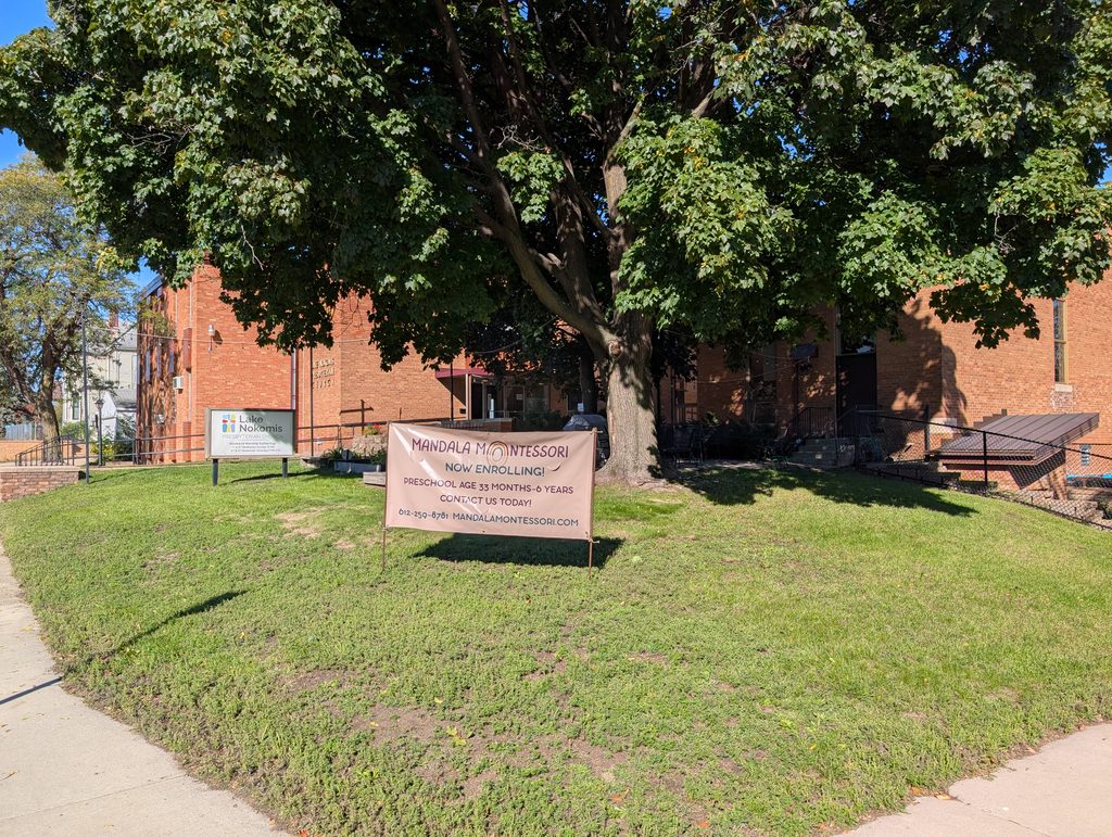 church behind a broad tree and a sign for Mandala Montessori