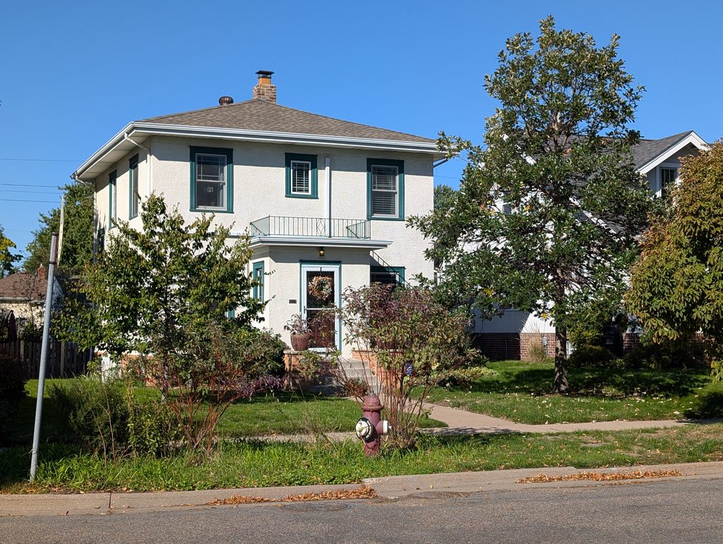 light colored two-story house with hipped roof