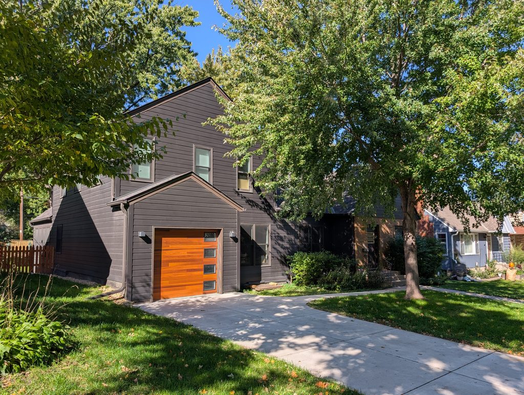 Dark two-story house with embedded garage with a door in warm wood tones