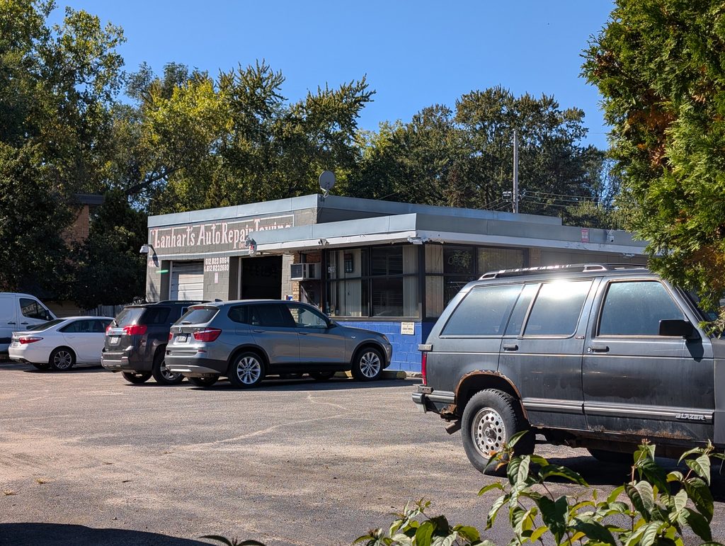 concrete block service garage with lower office area attached to it featuring a flat roof with wide eves and under it wide rectangular windows