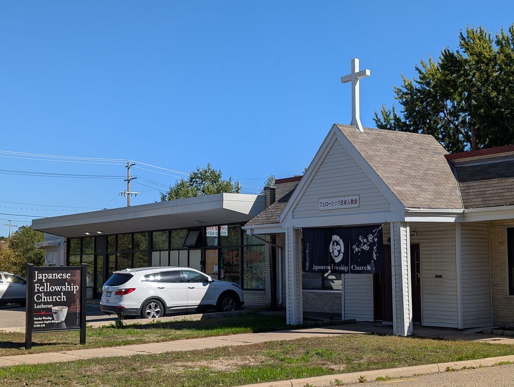 single-story building with cross on peak of portico roof and sign out front