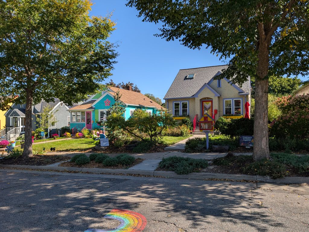 colorfully painted houses with rainbow on street in front