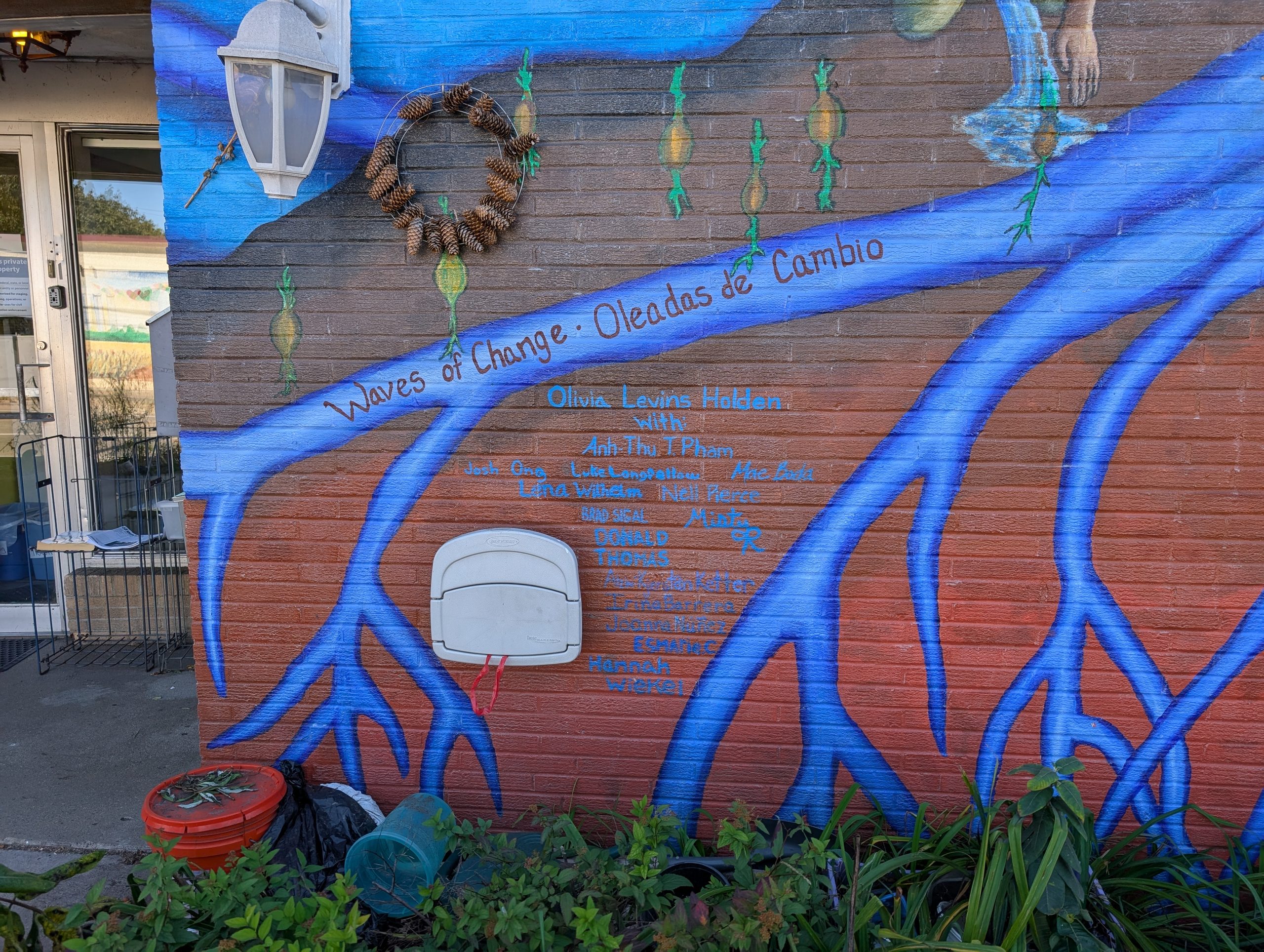 mural featuring blue roots branching downward against a rusty orange background