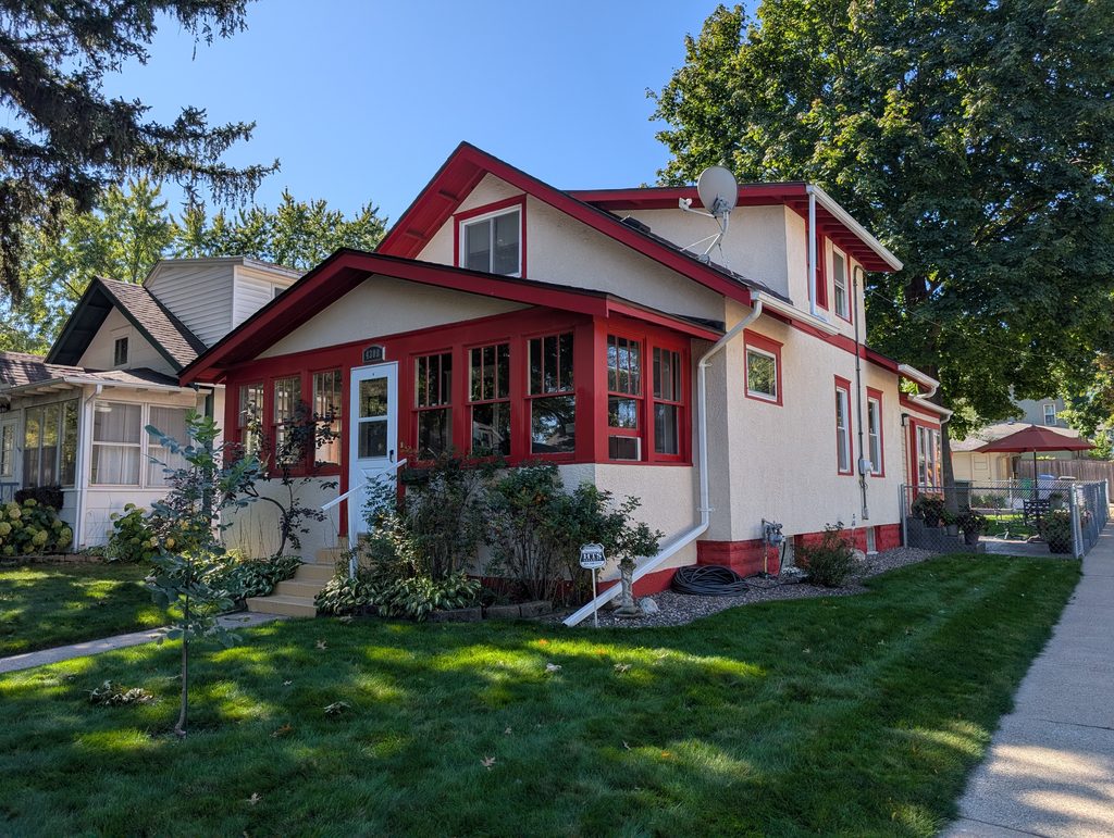 story-and-a-half house with prominent front porch and wide eaves with exposed rafters; double-hung windows are divided into panes in the upper sash but not the lower